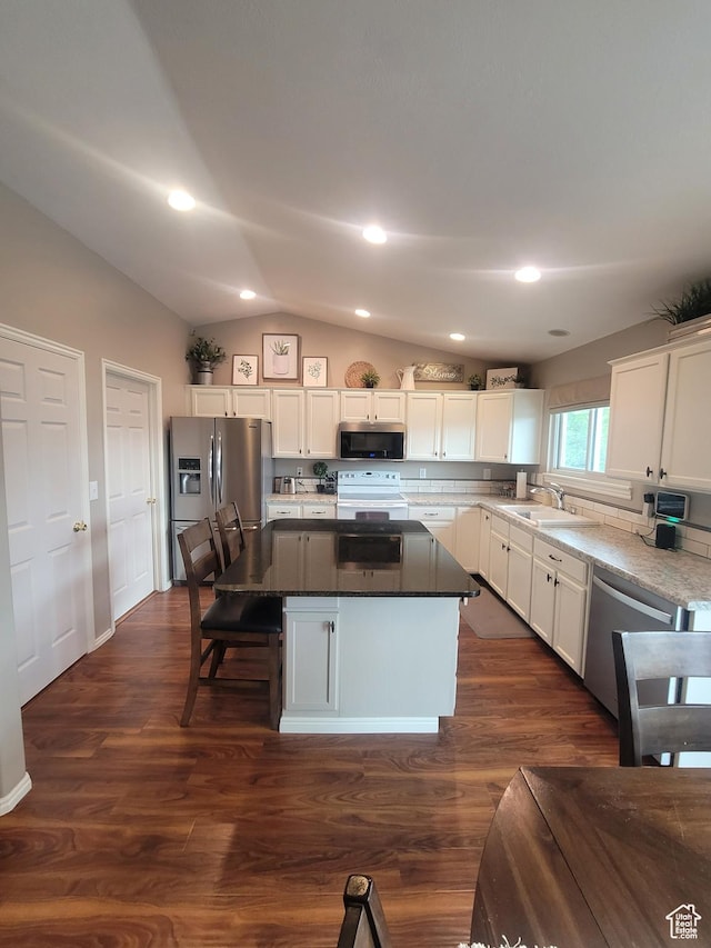 2981 S Pika Dr, West Valley City, UT 84128 - kitchen featuring stainless steel appliances, lofted ceiling, a kitchen island, white cabinetry, and dark wood finished floors
