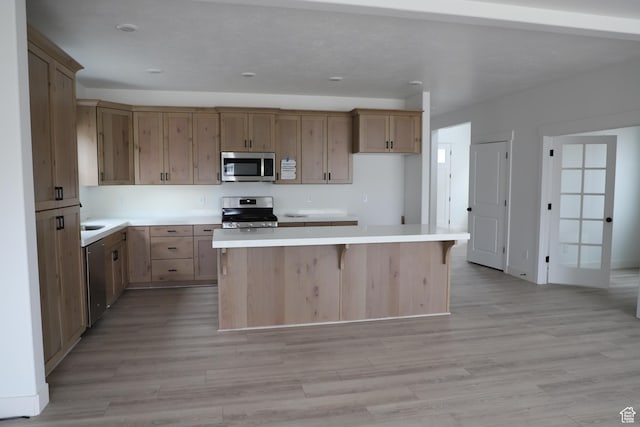 3736 N Janie St Unit 1005, Eagle Mountain, UT 84005 - kitchen featuring appliances with stainless steel finishes, a center island, light wood-style floors, light countertops, and a breakfast bar
