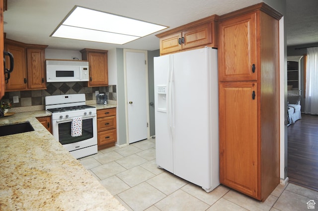 1185 W 725 N, Clearfield, UT 84015 - kitchen featuring white appliances, brown cabinets, light tile patterned floors, backsplash, and light stone countertops