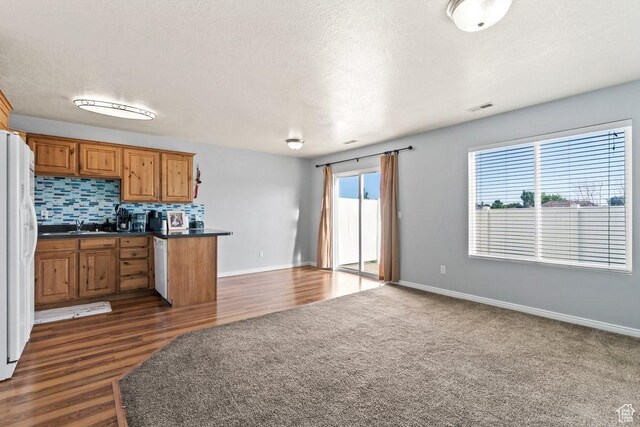 2856 W 3965 S Unit 78, West Haven, UT 84401 - kitchen with dark countertops, white fridge with ice dispenser, brown cabinets, tasteful backsplash, and open floor plan