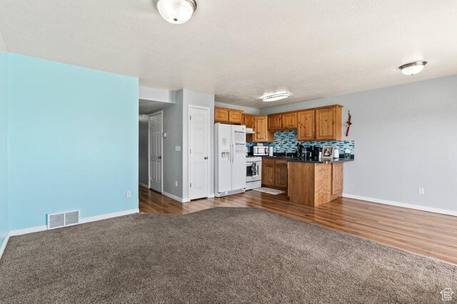 2856 W 3965 S Unit 78, West Haven, UT 84401 - kitchen with white appliances, dark countertops, brown cabinetry, open floor plan, and a textured ceiling