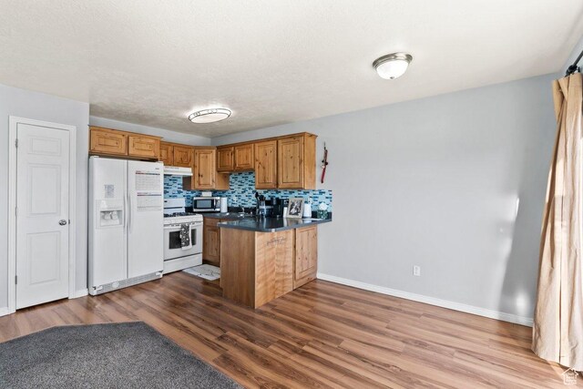 2856 W 3965 S Unit 78, West Haven, UT 84401 - kitchen with white appliances, a peninsula, wood finished floors, under cabinet range hood, and baseboards