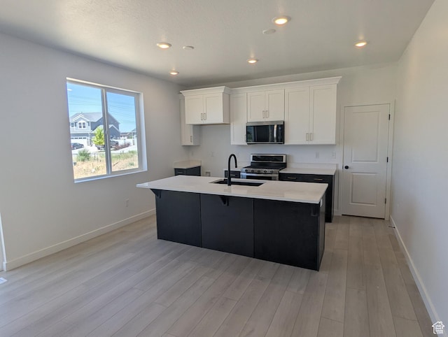 737 N Plainsman Dr Unit 108, Spanish Fork, UT 84660 - kitchen with stainless steel appliances, a kitchen island with sink, light wood finished floors, white cabinetry, and light countertops
