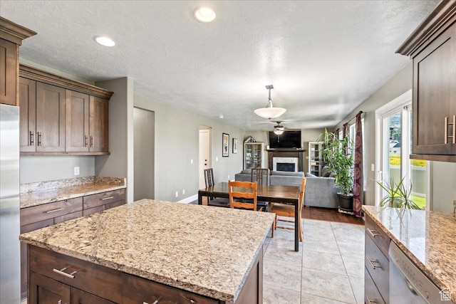 2007 N 850 E, North Ogden, UT 84414 - kitchen with stainless steel appliances, a fireplace, a center island, a textured ceiling, and light stone countertops