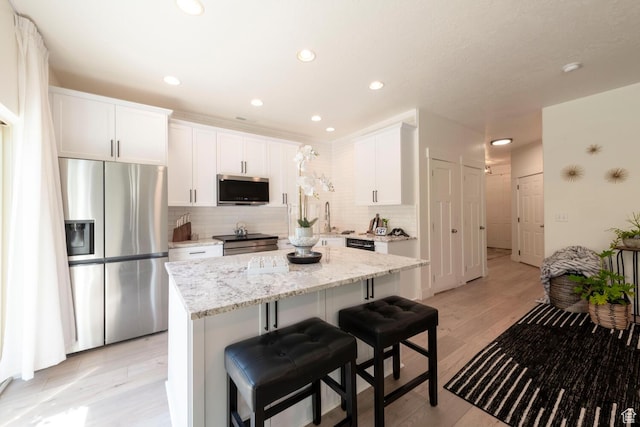 688 N 255 W, Centerville, UT 84014 - kitchen featuring stainless steel appliances, backsplash, a kitchen island, white cabinetry, and light stone countertops