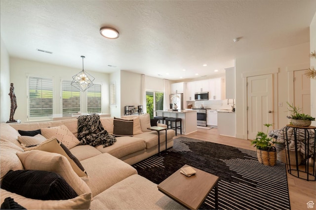 688 N 255 W, Centerville, UT 84014 - living area featuring light wood finished floors, plenty of natural light, a chandelier, and recessed lighting