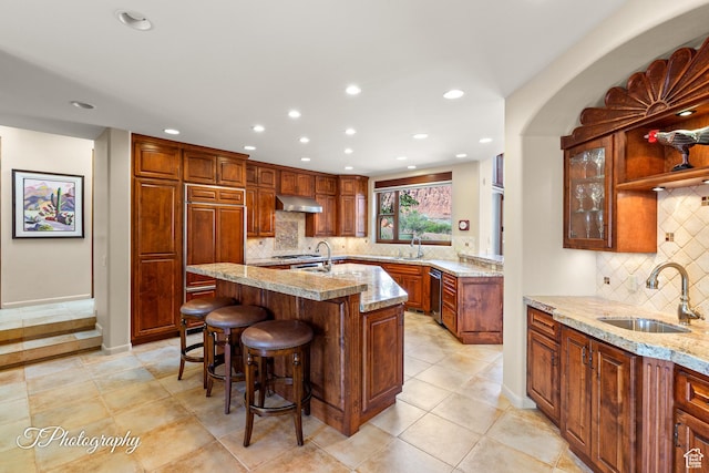 1936 N Uwan Dr, Ivins, UT 84738 - kitchen featuring a sink, recessed lighting, backsplash, light stone countertops, and a kitchen breakfast bar