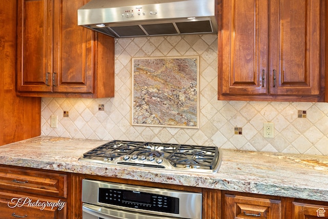 1936 N Uwan Dr, Ivins, UT 84738 - kitchen featuring extractor fan, appliances with stainless steel finishes, decorative backsplash, and light stone counters