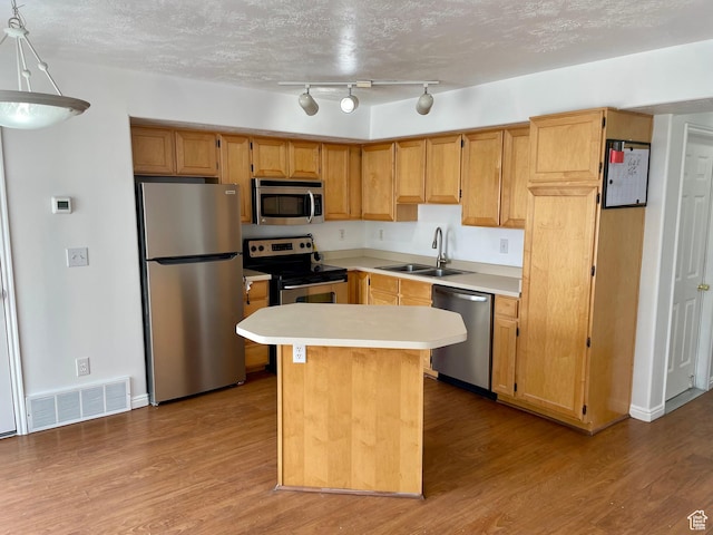 6939 S Florentine Way, West Jordan, UT 84084 - kitchen featuring stainless steel appliances, a sink, light countertops, wood finished floors, and a center island