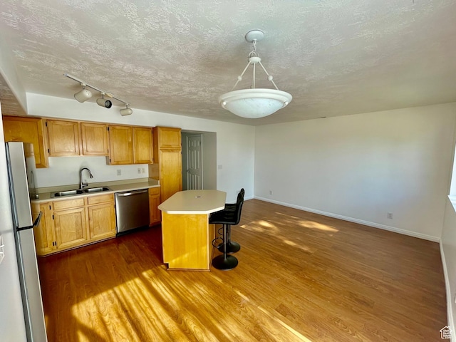 6939 S Florentine Way, West Jordan, UT 84084 - kitchen featuring appliances with stainless steel finishes, light countertops, dark wood-style flooring, a kitchen island, and a breakfast bar area