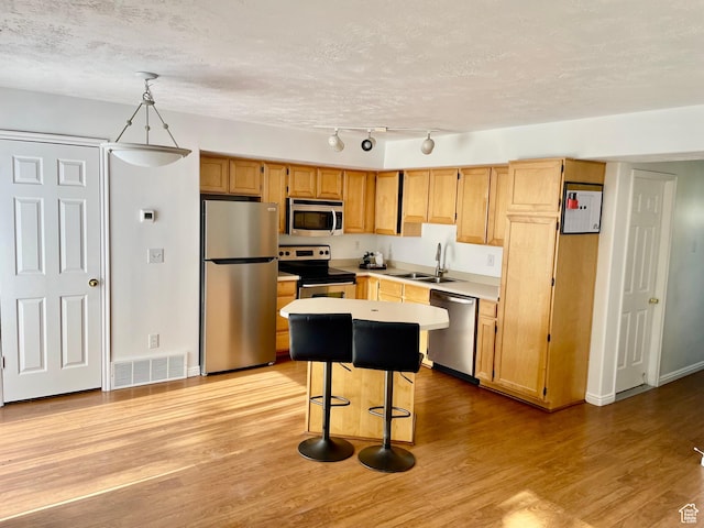 6939 S Florentine Way, West Jordan, UT 84084 - kitchen with stainless steel appliances, light countertops, light wood finished floors, a textured ceiling, and a kitchen breakfast bar
