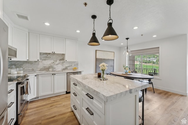 984 Uri Ln Unit 3, Midway, UT 84049 - kitchen with appliances with stainless steel finishes, a sink, backsplash, light wood finished floors, and a center island
