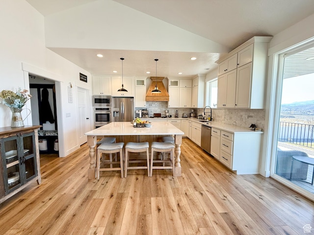 1384 E Abigail Ln, Eagle Mountain, UT 84005 - kitchen with stainless steel appliances, premium range hood, a sink, lofted ceiling, and light wood-style flooring