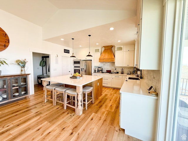 1384 E Abigail Ln, Eagle Mountain, UT 84005 - kitchen featuring appliances with stainless steel finishes, custom range hood, a kitchen island, a kitchen breakfast bar, and tasteful backsplash