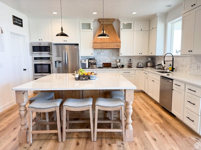 1384 E Abigail Ln, Eagle Mountain, UT 84005 - kitchen with appliances with stainless steel finishes, custom exhaust hood, a sink, tasteful backsplash, and a breakfast bar area