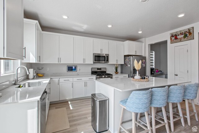 2503 N Velvet Moon Dr W Unit 636, Saratoga Springs, UT 84045 - kitchen with appliances with stainless steel finishes, a sink, light wood-style floors, a kitchen bar, and a center island