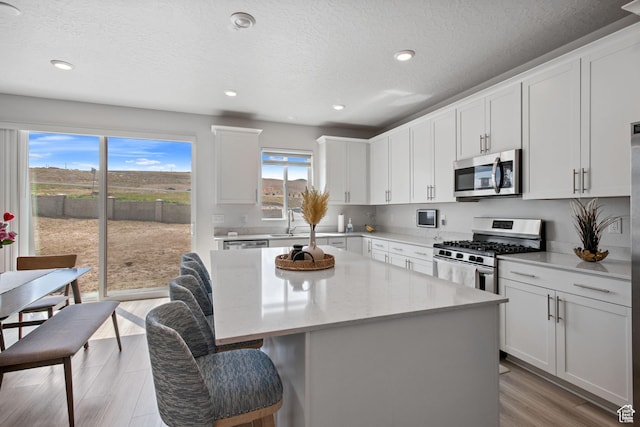 2503 N Velvet Moon Dr W Unit 636, Saratoga Springs, UT 84045 - kitchen featuring appliances with stainless steel finishes, a center island, a kitchen bar, a sink, and white cabinetry