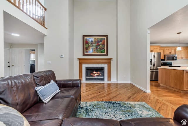 2825 Elk Horn Ln, Cottonwood Heights, UT 84093 - living room with light wood finished floors, a towering ceiling, a tiled fireplace, and baseboards
