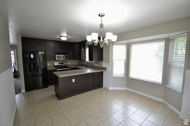 5057 W 6960 S, West Jordan, UT 84081 - kitchen featuring stainless steel appliances, a chandelier, a peninsula, a sink, and healthy amount of natural light