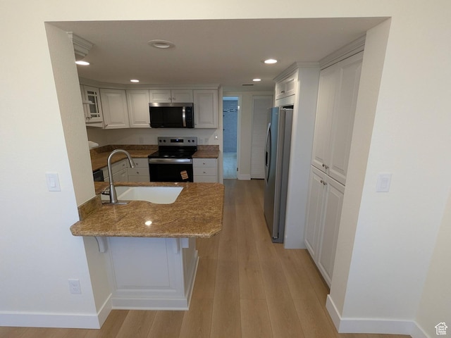 241 N Vine St W Unit 404E, Salt Lake City, UT 84103 - kitchen featuring stainless steel appliances, a sink, a peninsula, light stone counters, and light wood finished floors