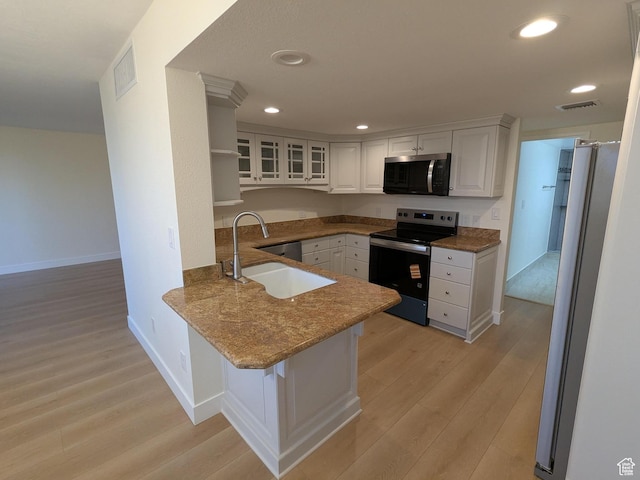 241 N Vine St W Unit 404E, Salt Lake City, UT 84103 - kitchen with stainless steel appliances, a peninsula, light wood-style flooring, white cabinets, and recessed lighting