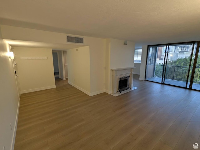 241 N Vine St W Unit 404E, Salt Lake City, UT 84103 - unfurnished living room featuring wood finished floors, baseboards, a wall of windows, and a high end fireplace