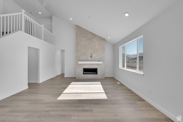 1089 S 3170 E Unit 205, Spanish Fork, UT 84660 - unfurnished living room featuring a tiled fireplace, recessed lighting, high vaulted ceiling, and wood finished floors