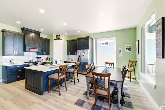 653 S 1140 E, Smithfield, UT 84335 - kitchen with appliances with stainless steel finishes, a breakfast bar area, backsplash, light countertops, and light wood-type flooring