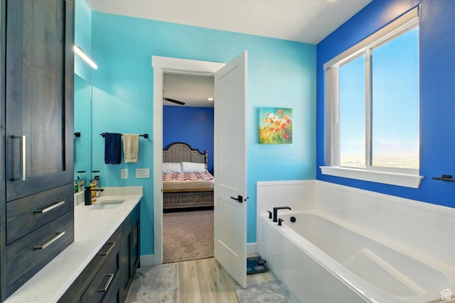 653 S 1140 E, Smithfield, UT 84335 - bathroom featuring wood finished floors, connected bathroom, vanity, a bath, and baseboards