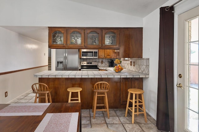 2263 W 4400 S, Roy, UT 84067 - kitchen with stainless steel appliances, tile counters, decorative backsplash, glass insert cabinets, and vaulted ceiling
