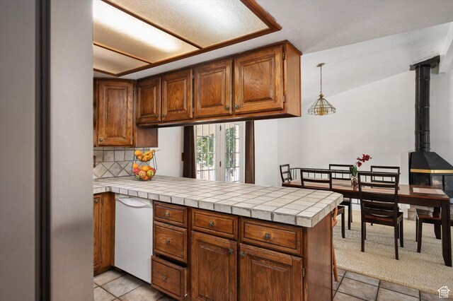 2263 W 4400 S, Roy, UT 84067 - kitchen featuring a peninsula, brown cabinetry, backsplash, light tile patterned floors, and white dishwasher