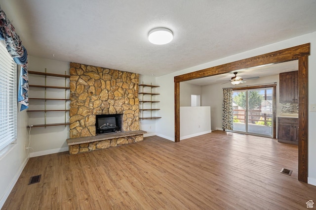 621 N 100 W, American Fork, UT 84003 - unfurnished living room with wood finished floors, baseboards, a textured ceiling, a stone fireplace, and ceiling fan
