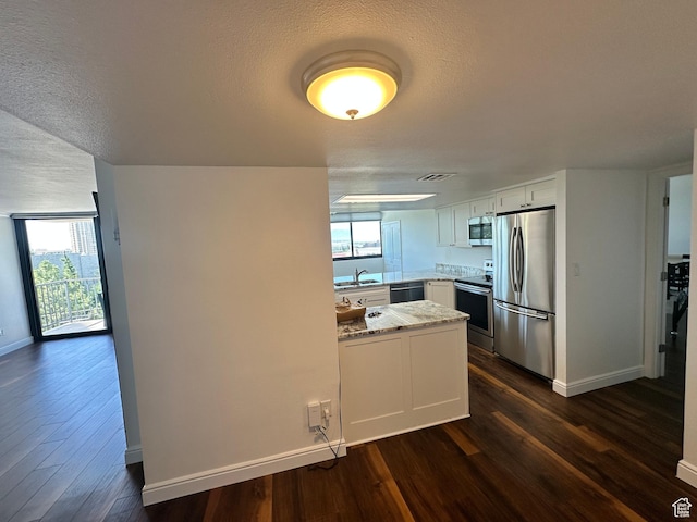 241 N Vine St E Unit 207W, Salt Lake City, UT 84103 - kitchen with stainless steel appliances, a peninsula, dark wood-style flooring, light stone counters, and a textured ceiling