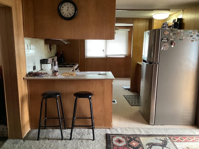 111 N 4th E, Manila, UT 84046 - kitchen with freestanding refrigerator, a peninsula, light colored carpet, brown cabinets, and under cabinet range hood