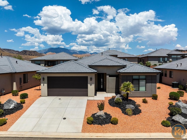 1060 W Jonathon Dr, Washington, UT 84780 - prairie-style house featuring an attached garage, driveway, stucco siding, and a mountain view