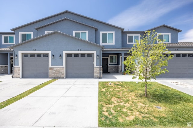 200 W 1200 S Unit 52, Tremonton, UT 84337 - view of front of house featuring driveway, stone siding, an attached garage, a front lawn, and stucco siding