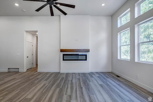 1605 S 1100 W, Payson, UT 84651 - unfurnished living room featuring wood finished floors, a glass covered fireplace, a ceiling fan, and recessed lighting