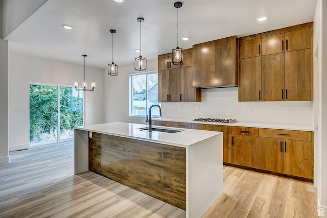 1605 S 1100 W, Payson, UT 84651 - kitchen featuring light wood finished floors, light countertops, a kitchen island with sink, a chandelier, and brown cabinetry