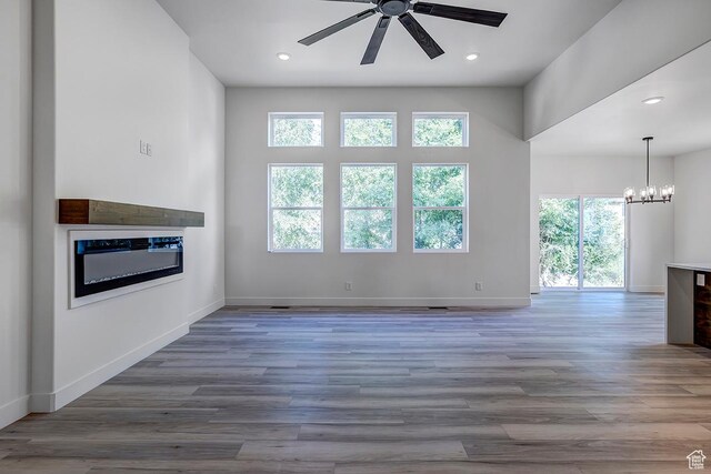 1605 S 1100 W, Payson, UT 84651 - unfurnished living room featuring a ceiling fan, a glass covered fireplace, wood finished floors, recessed lighting, and a chandelier