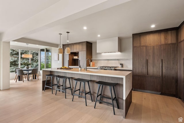 2655 E Hiawatha Cir, Salt Lake City, UT 84108 - kitchen featuring modern cabinets, tasteful backsplash, a breakfast bar area, light countertops, and light wood-style floors