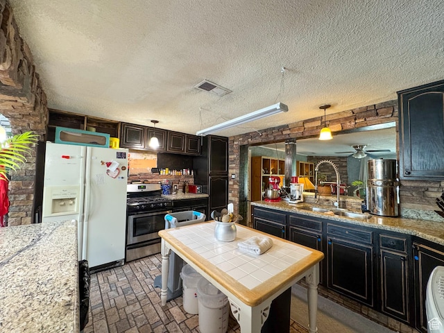 1204 S Redwood Dr, Salt Lake City, UT 84104 - kitchen featuring white fridge with ice dispenser, stainless steel gas stove, brick patterned flooring, a sink, and a textured ceiling