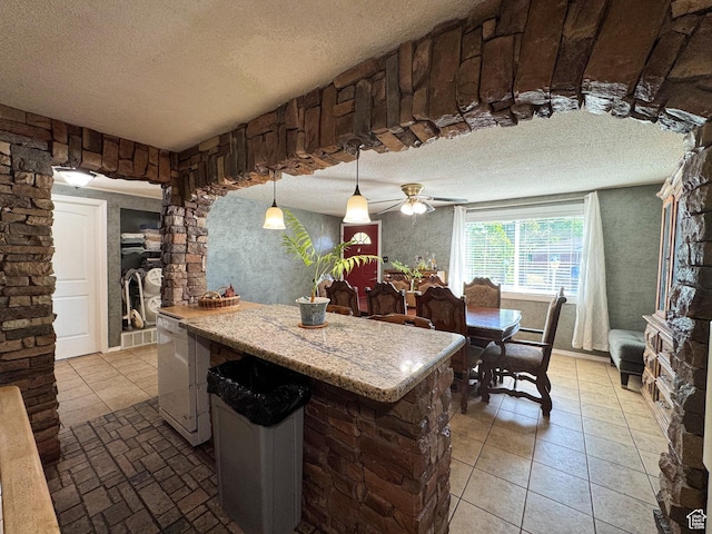 1204 S Redwood Dr, Salt Lake City, UT 84104 - kitchen featuring a textured ceiling, hanging light fixtures, a ceiling fan, a center island, and light tile patterned floors