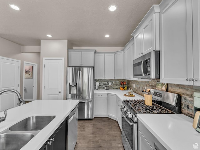 5636 W Lost Mine Ln, Herriman, UT 84096 - kitchen with stainless steel appliances, a sink, a textured ceiling, light countertops, and dark wood-style floors