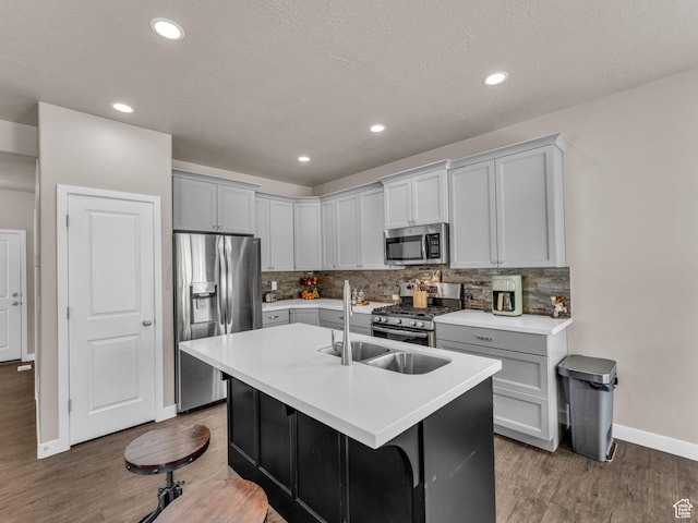 5636 W Lost Mine Ln, Herriman, UT 84096 - kitchen featuring appliances with stainless steel finishes, baseboards, light wood-type flooring, backsplash, and a kitchen island with sink