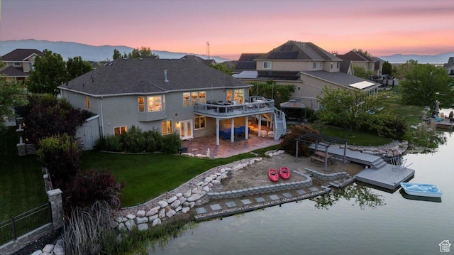 6142 N Schooner Ln, Stansbury Park, UT 84074 - back of property at dusk with a lawn, a deck with water view, a patio, and a residential view