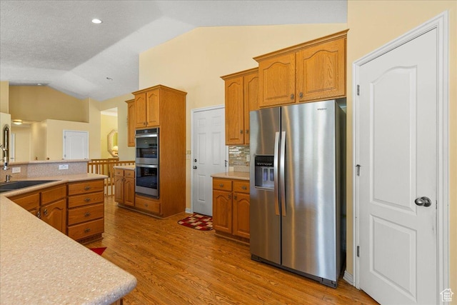 6142 N Schooner Ln, Stansbury Park, UT 84074 - kitchen featuring appliances with stainless steel finishes, lofted ceiling, light countertops, backsplash, and wood finished floors