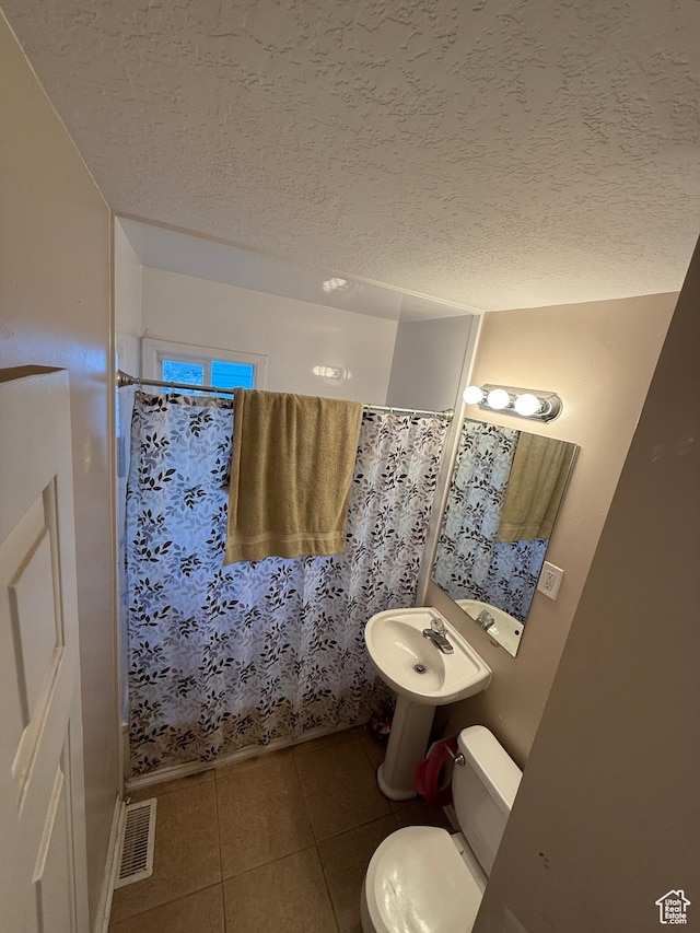 239 W Plum St, Grantsville, UT 84029 - bathroom with tile patterned floors, toilet, a textured ceiling, curtained shower, and a sink