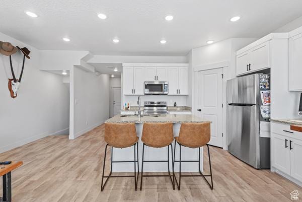 1024 E 1300 S Unit 31, Provo, UT 84606 - kitchen featuring appliances with stainless steel finishes, a kitchen bar, white cabinetry, a kitchen island with sink, and recessed lighting
