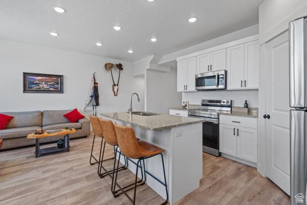 1024 E 1300 S Unit 31, Provo, UT 84606 - kitchen featuring appliances with stainless steel finishes, a sink, light stone countertops, recessed lighting, and a kitchen bar