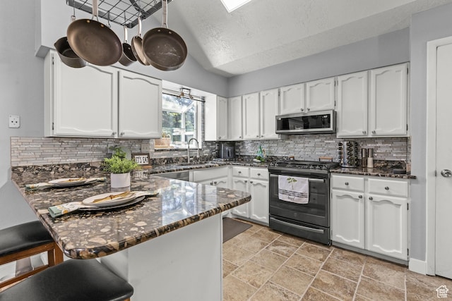 720 Freedom Cir N, Salt Lake, UT 84054 - kitchen with black gas range oven, stainless steel microwave, a peninsula, a sink, and white cabinets